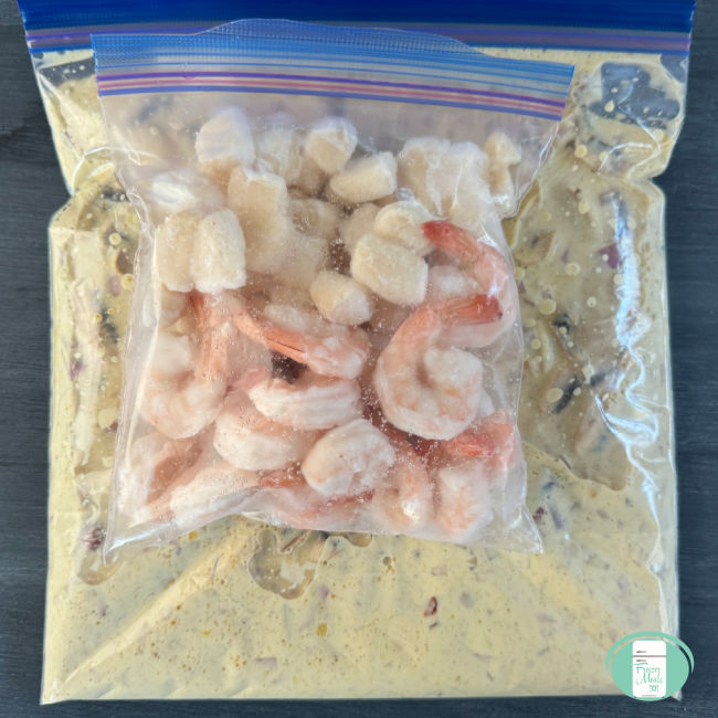 clear bag with yellow sauce with a smaller clear bag with shrimp and scallops in it