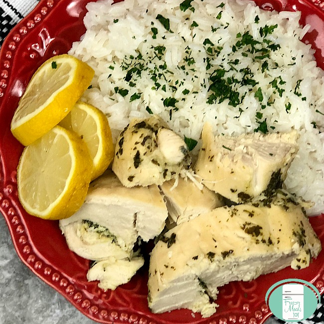close up of lemon garlic chicken with rice and lemon slices on the side, garnished with parsley