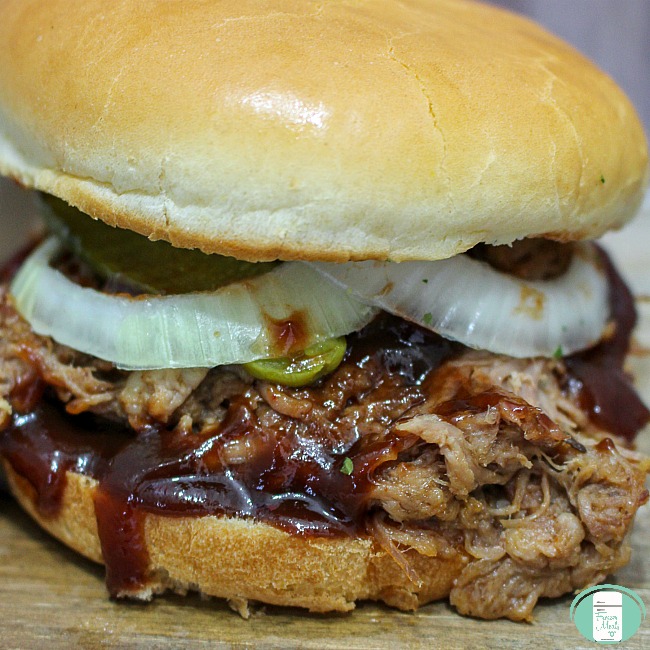 close up of pulled pork on a bun with sauce dripping out