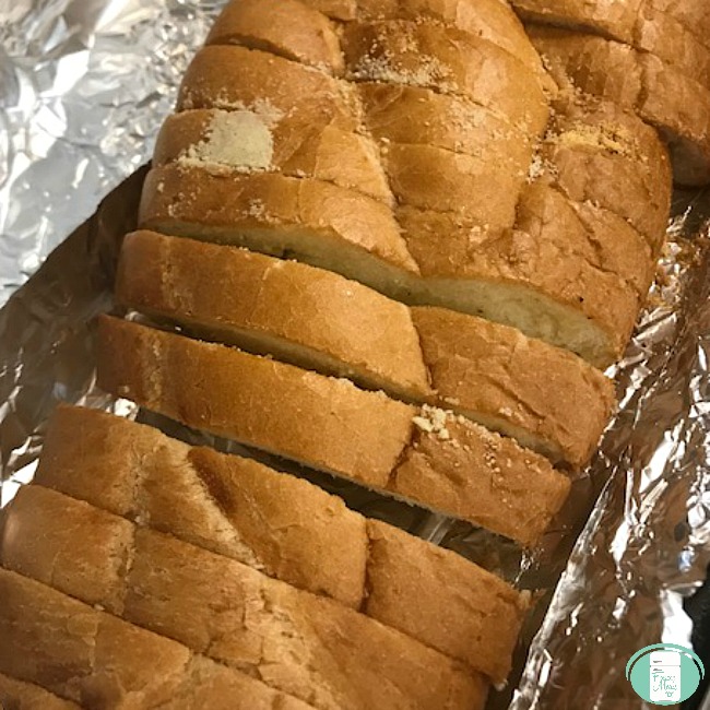 close up of a loaf of garlic bread sliced up on foil