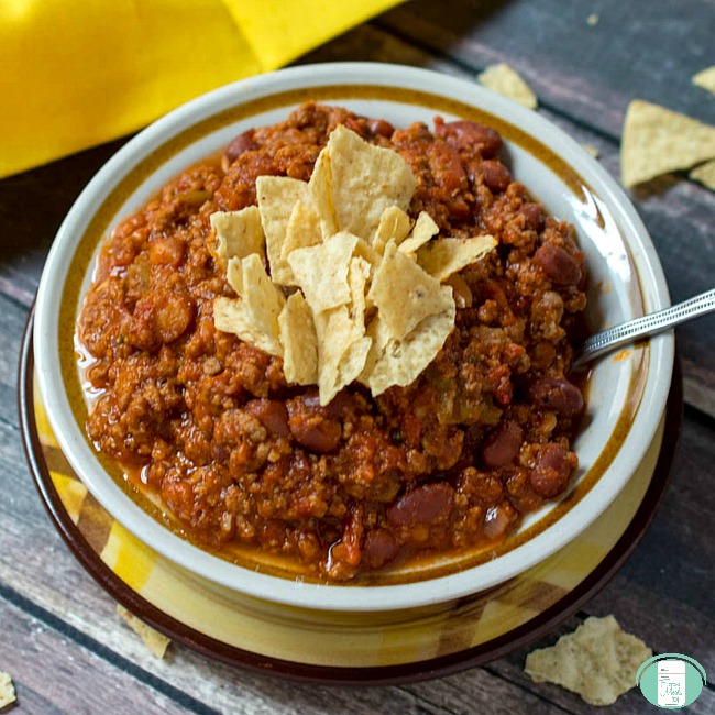 close up of thick and chunky chili in a bowl with pieces of tortilla chips on top