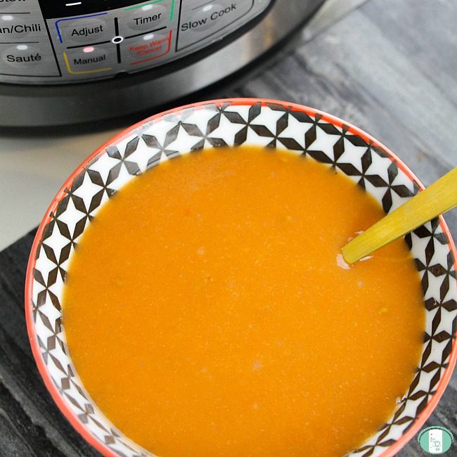 bowl of tomato soup with the instant pot it was made in off to the side