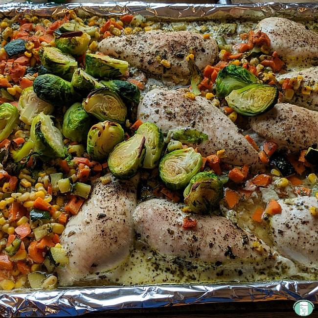 baking sheet with pesto chicken and vegetables, including brussels sprouts