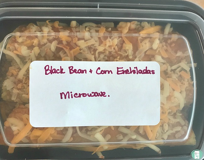 close up of black bean and corn enchiladas in a microwave-safe dish