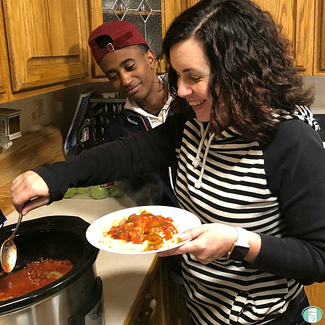 Sharla serving chicken cacciatore from the Crock-Pot to her teenage son
