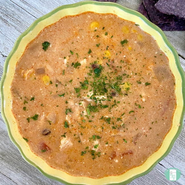 close up of crockpot enchilada soup garnished with parsley