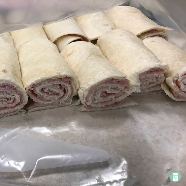 looking into a freezer bag with ham and cream cheese roll up sandwiches