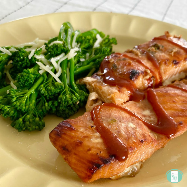 BBQ salmon on a plate, drizzled with BBQ sauce and broccoli on the side