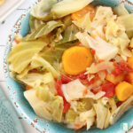 blue bowl heaped with vegetables like carrots, cabbage, tomatoes