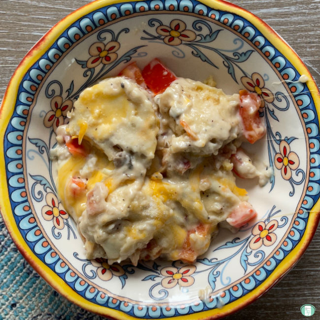pierogies smothered in cheese in a brightly coloured bowl