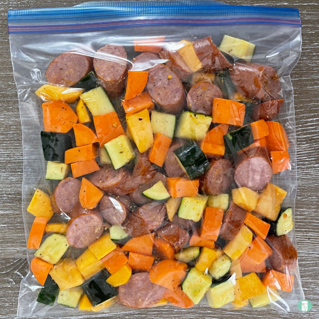sliced sausage and cubed root vegetables in a clear freezer bag