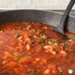 skillet with a ladle in it stirring hamburger goulash stew