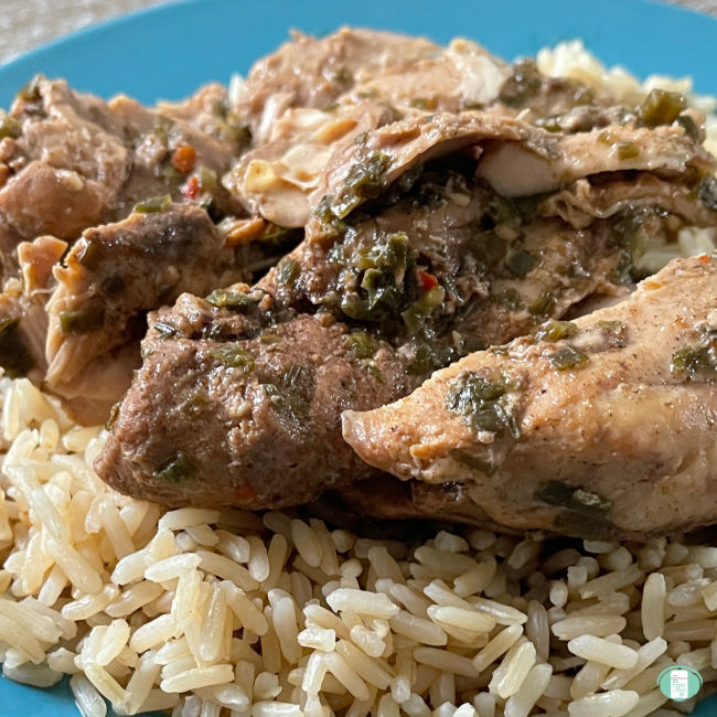 Jamaican Jerk chicken sits atop rice on a plate