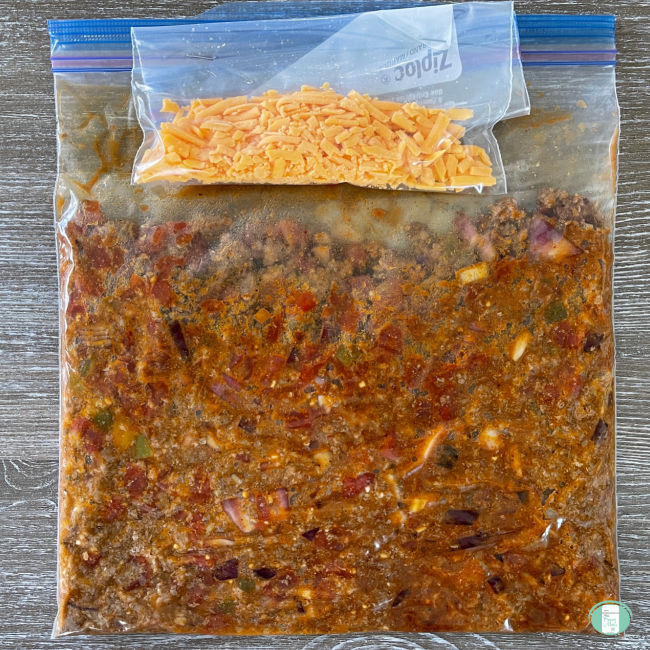 freezer bag with brown mixture in it and a smaller bag of cheese stapled to the top