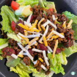 lettuce topped with taco meat, tomatoes, and shredded cheese