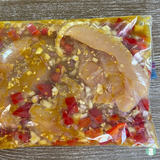 chicken and red peppers marinating in a clear bag