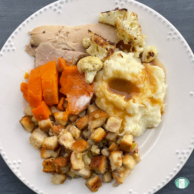 holiday plate of turkey, mashed potatoes, stuffing, sweet potatoes, and cauliflower