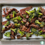 beef strips and broccoli on a cookie sheet