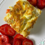 egg square on a plate next to sliced strawberries