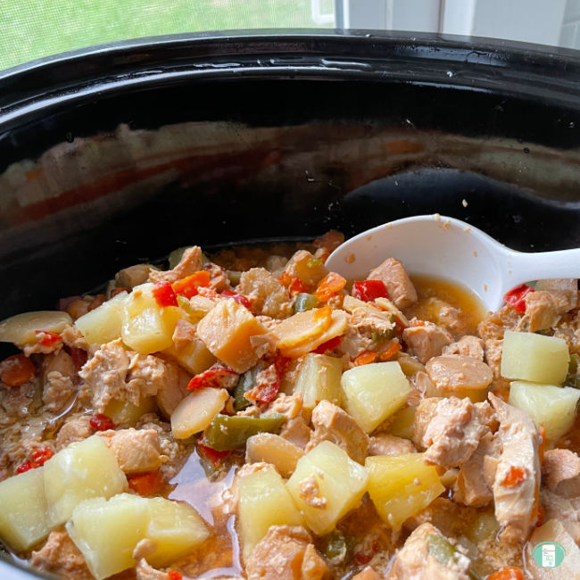 slow cooker filled with chunks of pineapple, chicken, and vegetables