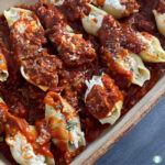tray of pasta shells stuffed and covered in red sauce