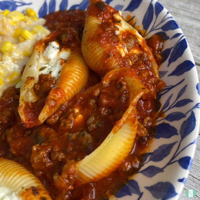 blue and white bowl filled with stuffed pasta shells in red sauce