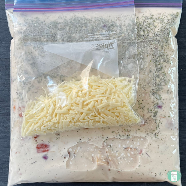 clear bag with whitish sauce and seasonings in it and a smaller clear bag with shredded cheese in it