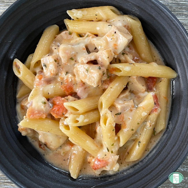 black bowl with penne pasta, chicken, and sauce
