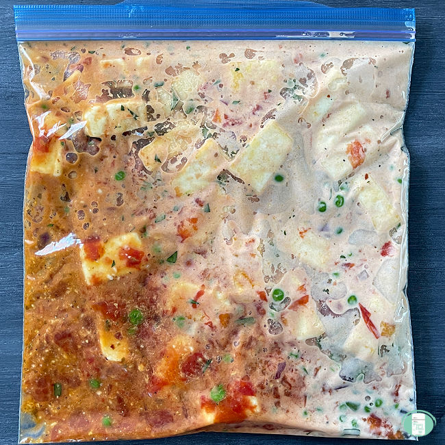 clear bag with cubed paneer in a sauce in it