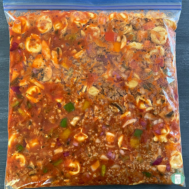 clear bag filled with tortellini, meat, vegetables, and sauce