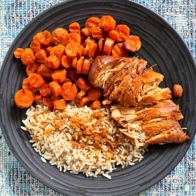 carrots, sliced chicken, and rice on a black plate