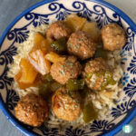plate with rice topped with meatballs, pineapple, and sauce