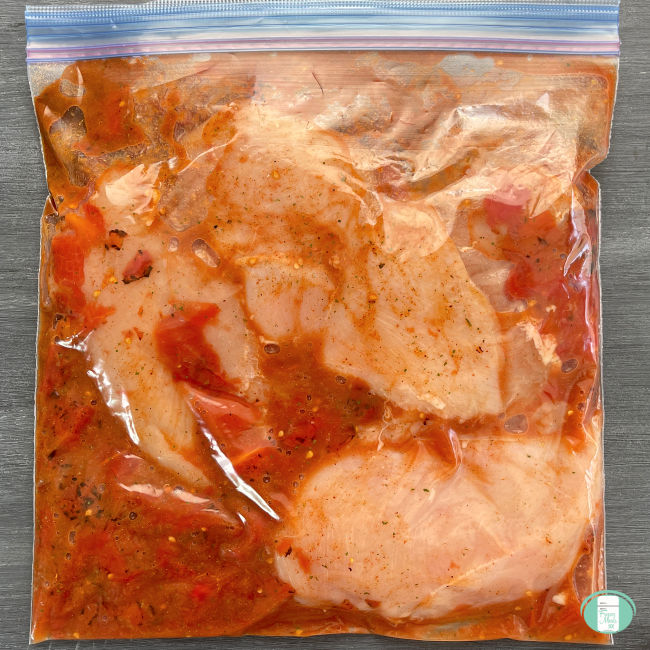 clear bag with chicken in a red sauce
