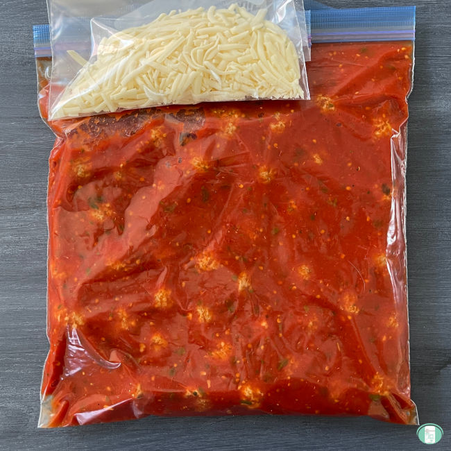 meatballs in red sauce in clear bag with another bag of shredded white cheese