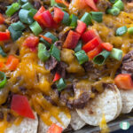 tortilla chips topped with melted cheese, shredded beef, tomatoes, and green onions