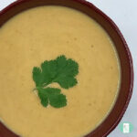 burgundy bowl with blended orange soup topped with fresh cilantro