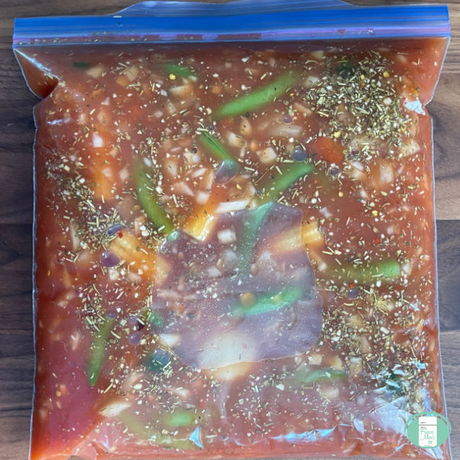 clear bag of red broth and vegetables