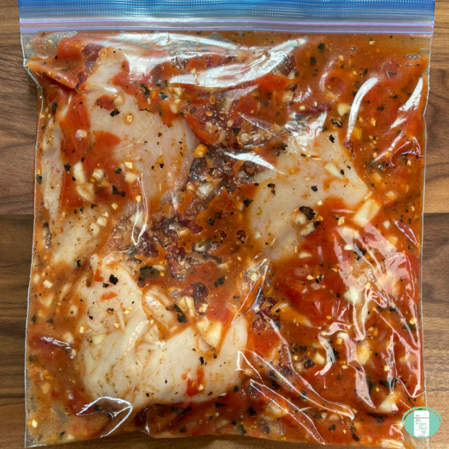 chicken in red marinade in clear bag