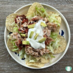 tortilla chips topped with lettuce, shredded chicken, and sour cream