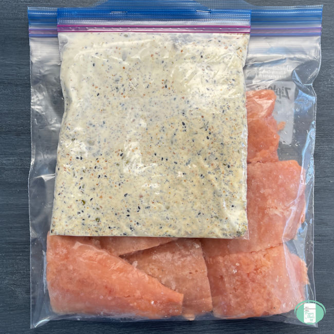 salmon in clear bag with a bag of white sauce on top
