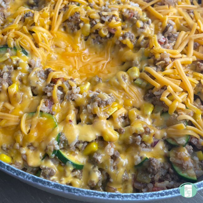 skillet of ground beef and rice topped with melted cheese