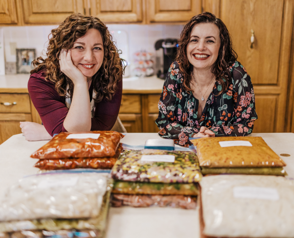 two women admire piles of freezer meals