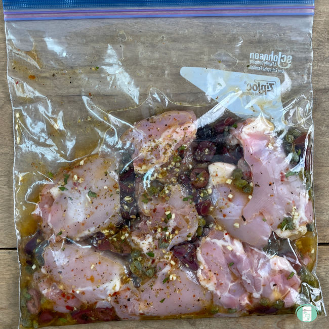 raw chicken with olives and seasonings in a clear bag