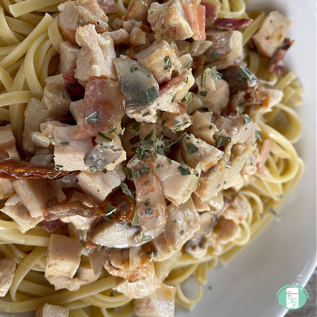 linguine noodles topped with cubes of cooked chicken, sliced mushrooms, sun dried tomatoes, and spices