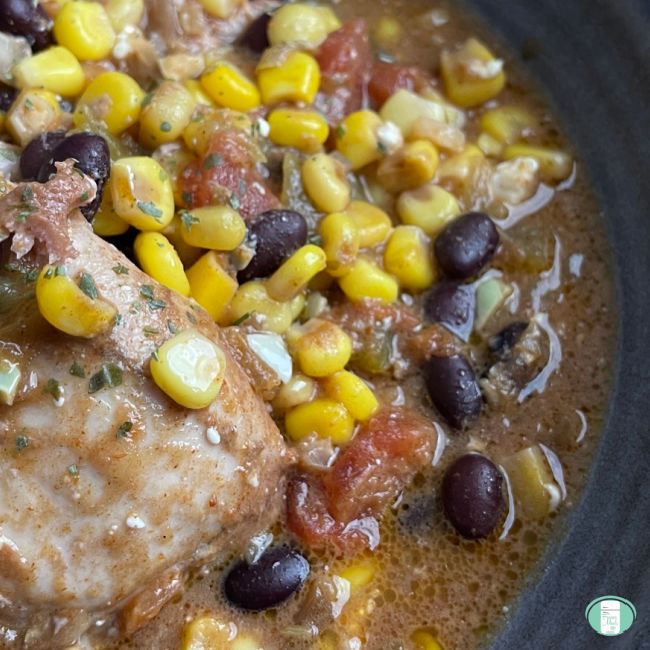 A close up of the Tex Mex chicken with diced tomatoes, kernel corn and black beans served in a black bowl.
