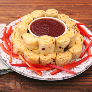 Christmas Pinwheels served with a festive wreath of sliced red peppers and a red dip