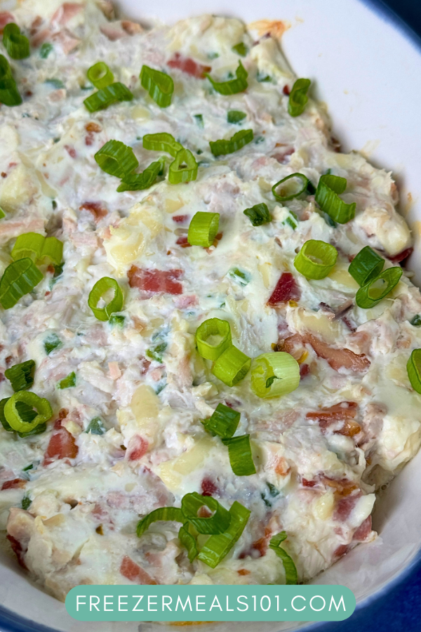 creamy white dip with pieces of bacon visible topped with sliced green onions