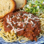 Spaghetti al tonno served in a white bowl with flaked tuna, fresh basil, and a rich tomato sauce.