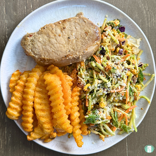 Plated steakhouse marinade porkchops with slaw and fries.