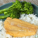 Plated Lemon Butter Cod served over white rice with steamed broccoli on a green plate.